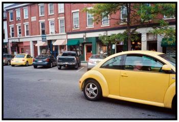 BELFAST – A pair of yellow Volkswagen Beetles flank a truck with a pair of yellow and black yin yang bumper stickers