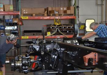 Framing the chassis begins with the frame rails arriving at the plant from a nearby foundry. The frames are aligned and the crossmembers bolted in. Then, the chassis is dried and painted. Here, Joel Bowser and Terry Hennessey calibrate the chassis. (Photo by Lynda Clancy)