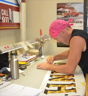 Chad Parker III has been in the Pierce graphic arts department for 31 years. Each community that engages Pierce to paint their crest on a new truck gets the attention of the graphic arts department, which specializes in gilding gold onto the truck body. "We Piercerize the trucks," said Parker. (Photo by Lynda Clancy)