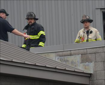 Rockland firefighter Francis Johnson and Asst. Chief Adam Miceli assess the roof of Knox County Jail for the source of smoke in the building. (Photo by Lynda Clancy)