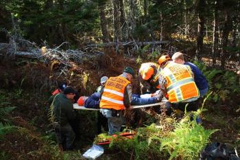 Now lying on a board, the volunteer victim suffering a hypothetical compound leg fractured, is passed up and out of the hole on Lasell Island. (Photo by Holly S. Edwards)
