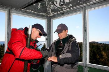 Andy Santheson and Rick Seibel dismantle the temporary radio communication equipment they set up earlier atop the Lasell Island fire tower for Saturday's mass casualty drill. (Photo by Holly S. Edwards)
