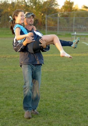 Oceanside's Erin Dugan, who was injured late in the game, gets carried off the field after the game by Chris Roman. (Photo by Ron Hawkes)