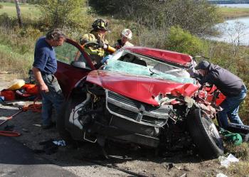 Firefighters use hydraulic extrication equipment while rescue crews tend to driver Eli Ranquist of Rockland after he crashed head-on into an oncoming Freightliner flatbed truck Monday afternoon in Cushing. (Photo courtesy Rockland Fire Department/Alan Athearn)