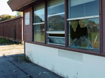 A cinder block was used to smash a hole in this window at the back corner of the closed MacDougal School on Broadway in Rockland. (Photo by Holly S. Edwards)