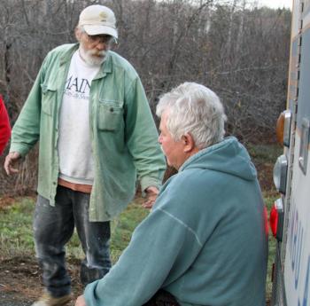 Ray Lovejoy, seated, and his neighbor, Ron Moran, talk about making repairs to his home following Monday's accident. (Photo by Holly S. Edwards)