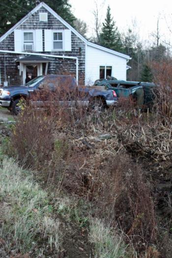 The Subaro went off the road, went through the ditch in the foreground, struck the back of the pickup truck and then the house. (Photo by Holly S. Edwards)