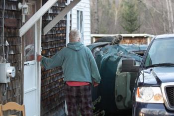 Ray Lovejoy pauses to look at the crashed car in his driveway Monday afternoon, before going back inside his home. (Photo by Holly S. Edwards)