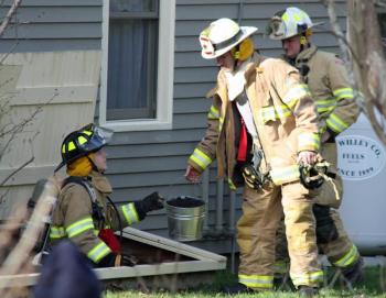 From left, Camden firefighter Scott Entwistle passes a bucket of debris cleared from inside the chimney to Asst. Chief Andrew Lowe, with Chief Chris Farley in the back. (Photo by Holly S. Edwards)