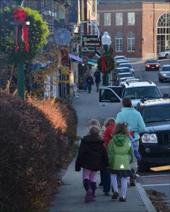 Jackie Grannis-Phoenix leads several of her Blue Door Montessori School students down Main Street in Camden, along the decorated sidewalks hung with wreaths. (Photo by Lynda Clancy)