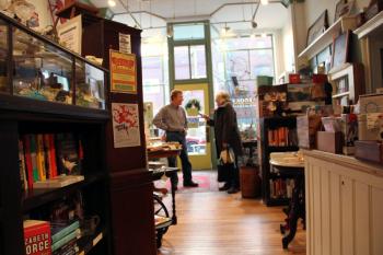Jean Watts of Glenburn talks to Bella Books co-owner Gary Guida on Thursday. The store is one of many in downtown Belfast opening at 6 a.m. this Saturday for the annual Early Bird Sale. (Photo by Wes Sterrs)