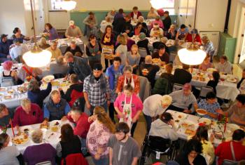 As the dining hall fills with people, volunteers hurry about to start serving meals. (Photo by Chris Wolf)