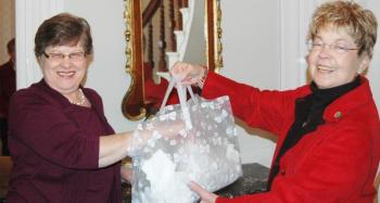 Hospital Aid President Phyllis Gaul, left, draws the winning raffle tickets from a bag held by Sally Millhorn. (Photo courtesy Toni Mailloux)