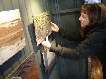 Karen Miles of Wanderbird Expedition Cruises and Northern Lights Gallery hangs a painting by Lisa Lebofsky made during a voyage loosely retracing the 1869 Arctic expedition of painter William Bradford. (Photo by Ethan Andrews)