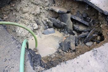 Two pumps are being used to lower the water level inside the hole between diggings of dirt, gravel, rocks and pavement. (Photo by Holly S. Edwards)