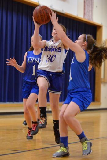 Hope's Bella Merrill, center, draws the foul from Lincolnville's Izzy Lang on the shot. (Photo by Ron Hawkes)