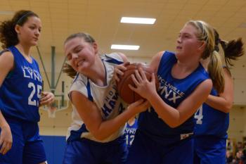 Lincolnville's Mya Wiley, right, and Hope's Kira Barley battle for the ball off a rebound while Lincolnville's Tora Decker-Griffith. Hope won the quarterfinal playoff game 45-36. (Photo by Ron Hawkes)