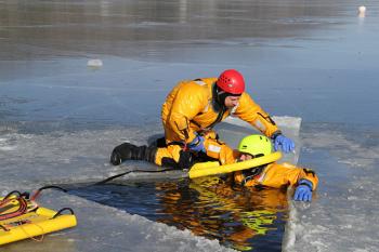 Firefighter Brian Sullivan puts the ring around Mike Cole in prepartion for getting him onto the sled, out of the water. (Courtesy Rockland FD/by Alan Athearn)
