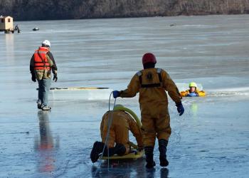 A team heads out onto the pond to make the rescue during training Saturday with an ice fisherman in the background. (Photo by Holly S. Edwards)