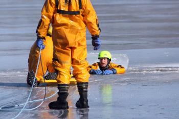 Firefighter Mike Cole is in the water as Brian Sullivan slides closer on the ice rescue sled. (Photo by Holly S. Edwards)