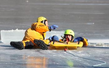 Firefighter Brian Sullivan signals to the team on land to begin pulling the line to pull Mike Cole out of the water and onto the rescue sled. (Photo by Holly S. Edwards)