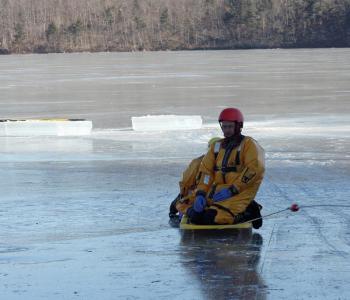 Second ice rescuer, firefighter Carl Anderson, climbs aboard the sled for the ride back to shore. (Photo by Holly S. Edwards)