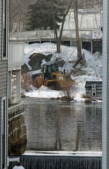 Moments after the 911 call, a front-end loader can be seen down an embankment at the mill pond above Knox Mill in downtown Camden. (Photo by Holly S. Edwards)