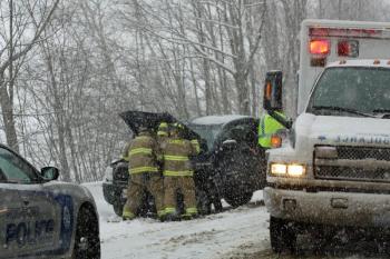 Camden firefighters disconnect the battery in Judith Carver's totalled Toyota pickup truck after she crashed it on Route 52 Sunday afternoon. (Photo by Holly S. Edwards)