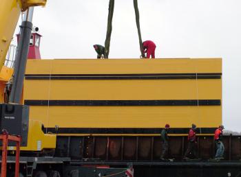 Workers unhitch crane straps from a massive fiberglass and concrete dock fender after it was loaded onto a barge in Belfast Thursday. (Photo by Ethan Andrews)