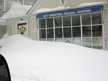 Many buildings downtown looked like the one housing Global Packing and Shipping on upper Washington Street by Saturday afternoon. It will take a while Sunday for businesses and residents to dig out, but sunny weather Sunday will make the going a little easier. (Photo by Holly S. Edwards)