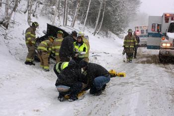 Camden First Aid Association emergency medical technicians prepare to transport Cheryl Battles, of Camden, to the hospital while Camden firefighters check out the Chevrolet sport utility vehicle Battles was a passenger in following a crash on Route 52 early Sunday afternoon. (Photo by Holly S. Edwards)