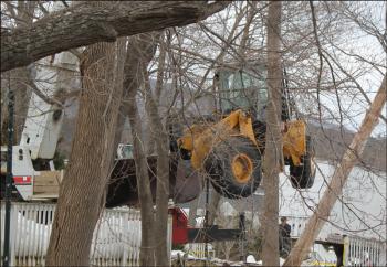 Soon after 9 a.m. on Saturday, Feb. 16, the front-end loader that had tumbled over the side of a 20-foot wall the previous day was being lifted back up from the river's edge with a crane. (Photo by Lori Van Dusen)