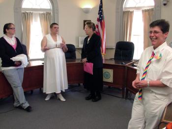 Gabrielle Eiholzer, far right, and Opal Ash, second from left, dressed in white with rainbow accents for their wedding at City Hall, Feb. 25, the first marriage of a same-sex couple in Belfast. (Photo by Ethan Andrews)