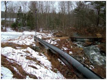 The penstock at Mason Pond diverts water into a generating station, while the river travels on at right. (Photo by Ethan Andrews)