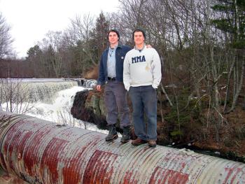 Nicholas Cabral, left, and Nicholas Berner on the penstock at Mill Dam, part of the Goose River hydroelectric generating system they recently bought and plan bring back online. (Photo by Ethan Andrews)