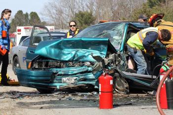 CFAA Access Team members work to cut the doors and frame of the Ford Escort to allow removal of the injured driver, Terry Ripley of Northport. (Photo by Holly S. Edwards)