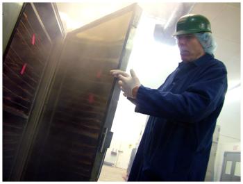 Ducktrap River of Maine's longtime smokehouse operator, Leo Lynch, shows the racks of salmon inside one of the Belfast facility's smokers. (Photo by Ethan Andrews)