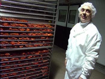 Dennis Harris, plant manager for Ducktrap River of Maine, stands by racks of smoked salmon inside the company's Belfast processing facility. On Tuesday, Ducktrap announced plans for a major expansion of the building aimed at keeping pace with business, which has doubled in the last four years. (Photo by Ethan Andrews)