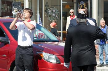 Camden Hills Regional High School band member Aaron Nolan plays taps while Ray Lewis, of American Legion Post 30, prepares to lay a wreath at the Honor Roll on Camden's village green during Monday morning's Memorial Day Parade. (Photo by Holly S. Edwards)