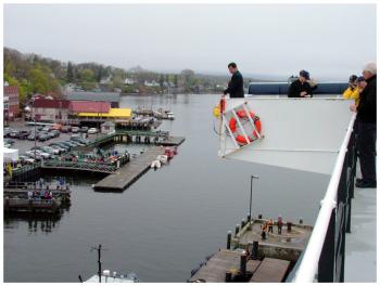 Capt. David Gelinas of the Penobscot Bay & River Pilots Association looks down at the water in Castine Harbor from the upper deck of Maine Maritime Academy's Training Ship State of Maine for clues about the direction of the tide. (Photo by Ethan Andrews)