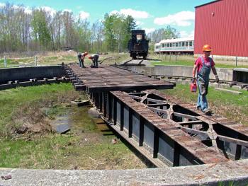 Workers dismantle the old Belfast and Moosehead Lake Railroad turntable at Unity Station, May 8. Some of the equipment is bound for the Great Smoky Mountain Railroad in North Carolina. Other pieces, including several train cars are reportedly headed to a museum in Tennessee. (Photo by Ethan Andrews)