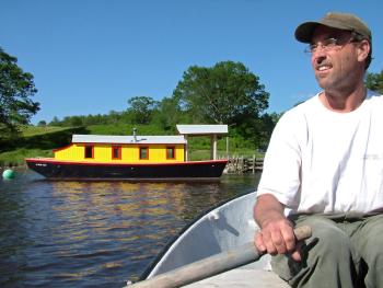 Maynard Haslett, of Washington, rows a dingy out to his 30-foot riverboat, "Shanty," anchored in the Passagassawakeag River in Belfast. (Photo by Ethan Andrews)