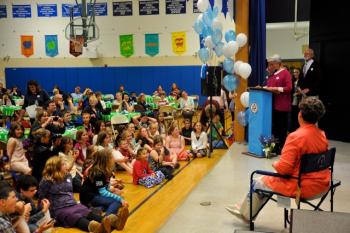 Carol Hathorne sitting in her personalized camp chair with many eyes on her, Ann Bresnahan speaking.