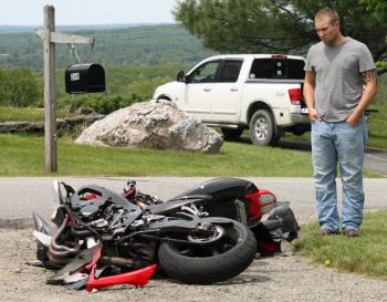 Vernon Kvorjak of Owls Head and his broken Suzuki motorcycle on Mill Street in Rockport late Monday morning. (Photo by Holly S. Edwards)