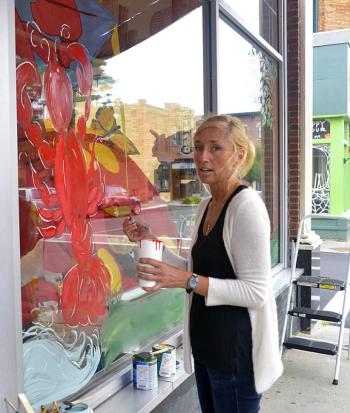 Marjanne Raddmaker of Owls Head paints the windows of Planet Toys for the Lobster Festival that begins Wednesday. (Photo by Ron Hawkes)