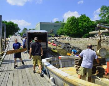 Camden's Chief Deputy Harbor Master Jim Leo, Fire Chief Chris Farley, Greg Sarno, and Jeremy and Shannon Hay move the merchandise to the Welcome, Camden's gunboat.