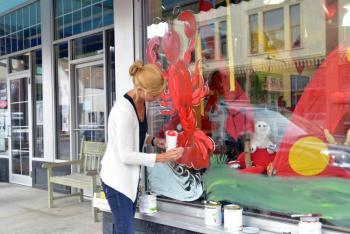 Marjanne Raddmaker of Owls Head paints the windows of Planet Toys for the Lobster Festival that begins Wednesday. (Photo by Ron Hawkes)