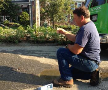 Hank Merchant, who works for Maine Water, arrived to test the water in the puddle. If it turns pink, it contains chlorine, indicating its source is the Maine Water main. (Photo by Lynda Clancy)