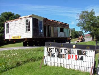 As advertised: The old East Knox School passes by the town office Wednesday morning en route to its new home at Thor-Nox Farms on Route 220. (Photo by Ethan Andrews)