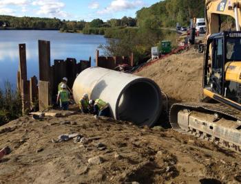 One of 15 concrete culvert pieces gets laid into the deep ditch separating Tolman Pond in Rockport with the wetlands on the other side of the highway. (Photo by Lynda Clancy)